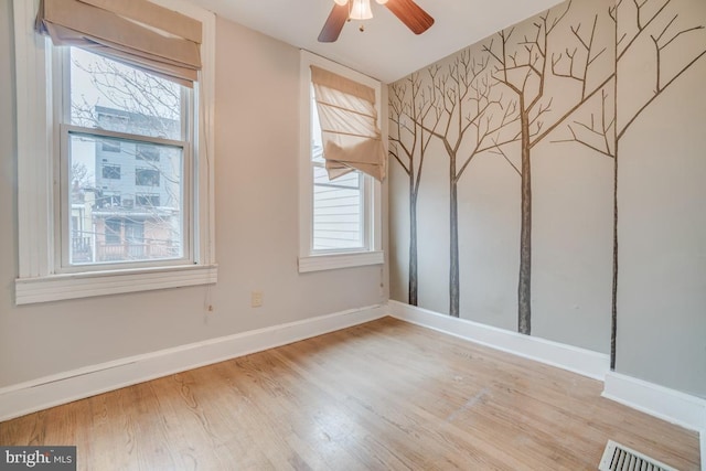 unfurnished room with baseboards, a ceiling fan, visible vents, and wood finished floors