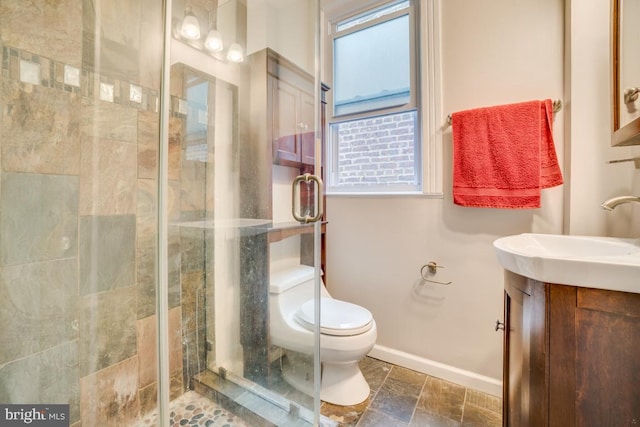 full bathroom with a stall shower, toilet, baseboards, stone finish flooring, and vanity