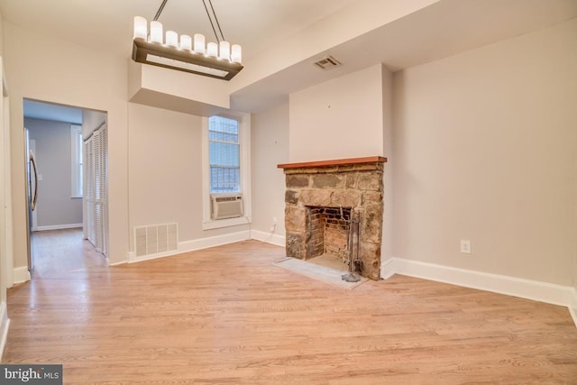 unfurnished living room featuring baseboards, a stone fireplace, visible vents, and wood finished floors