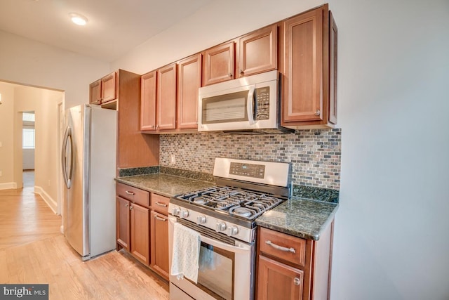 kitchen featuring brown cabinetry, stainless steel appliances, backsplash, and light wood-style floors