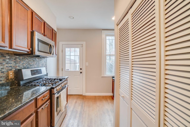 kitchen with brown cabinets, stainless steel appliances, baseboards, light wood-style floors, and decorative backsplash