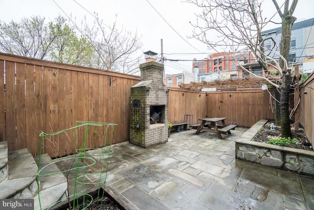 view of patio / terrace featuring a fireplace and a fenced backyard