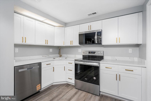 6317 Park Heights Ave Unit 616, Baltimore, MD 21215 - kitchen with light wood finished floors, visible vents, a sink, stainless steel appliances, and white cabinets