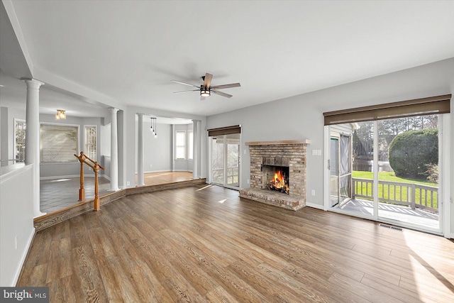 10288 Broken Sound Blvd, Ocean City, MD 21842 - unfurnished living room with decorative columns, a ceiling fan, wood finished floors, a brick fireplace, and baseboards