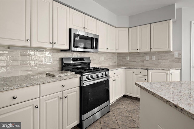10288 Broken Sound Blvd, Ocean City, MD 21842 - kitchen with appliances with stainless steel finishes, white cabinetry, tasteful backsplash, and light stone counters