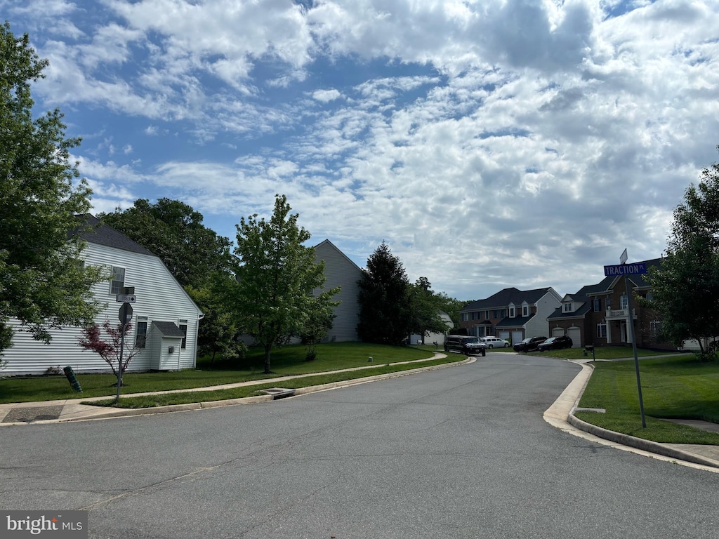 view of asphalt street with sidewalks, curbs, and a residential view