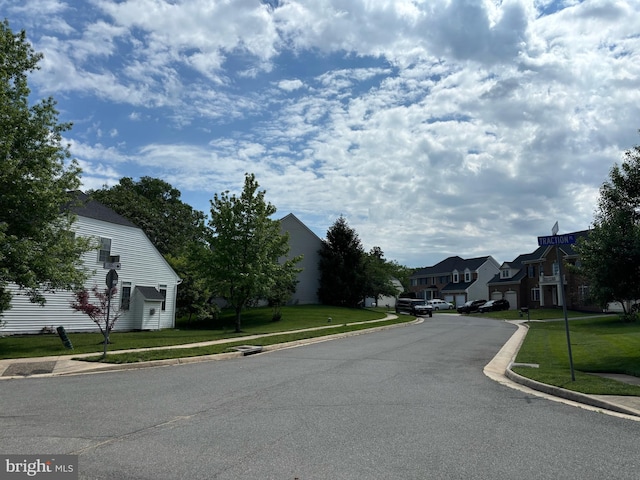 view of asphalt street with sidewalks, curbs, and a residential view
