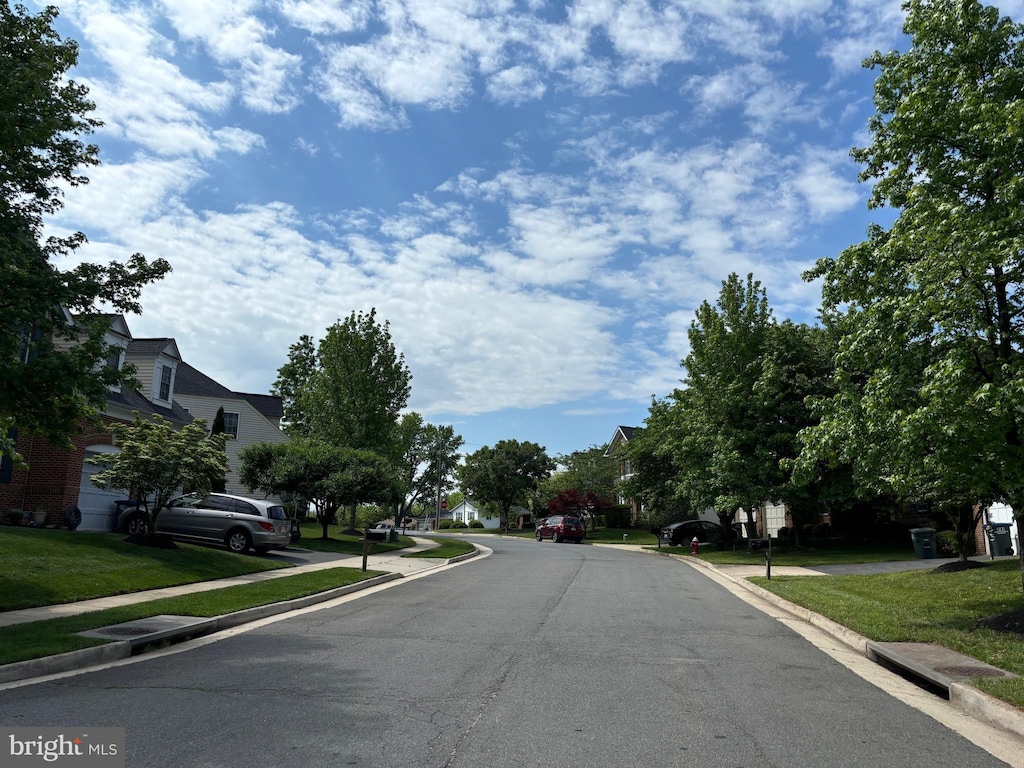 view of asphalt street with curbs, sidewalks, and a residential view