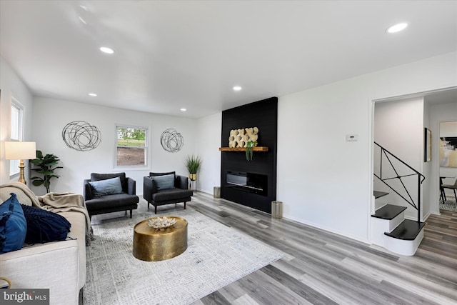 living area with wood finished floors, stairway, recessed lighting, a fireplace, and baseboards