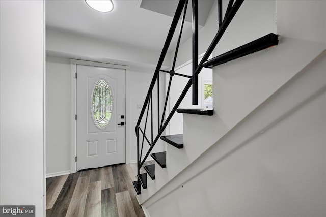 foyer entrance with stairs, wood finished floors, and baseboards