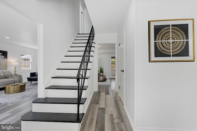 staircase with wood finished floors and recessed lighting