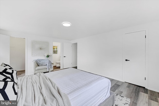 bedroom featuring wood finished floors and ensuite bath
