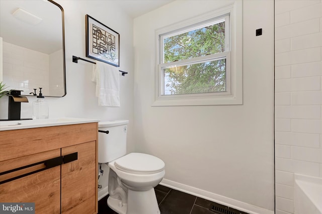 bathroom featuring tile patterned flooring, toilet, baseboards, vanity, and a bath