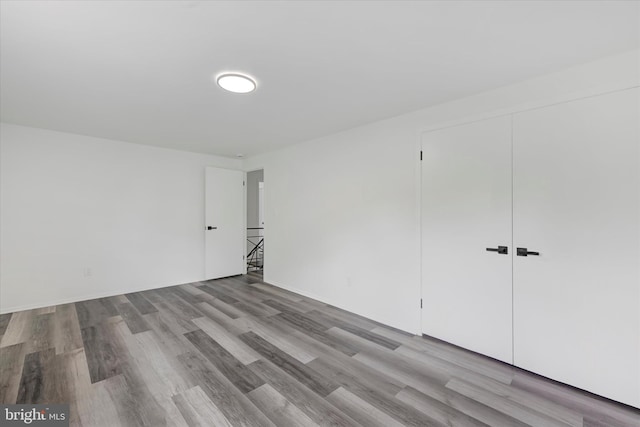 unfurnished bedroom with wood finished floors and a closet