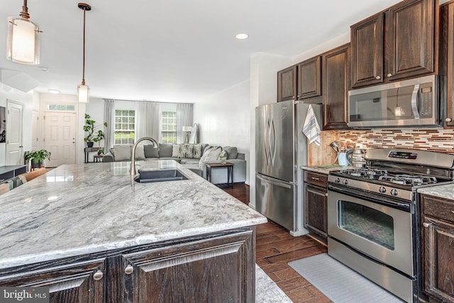 11972 Tygart Lake Dr, Bristow, VA 20136 - kitchen featuring stainless steel appliances, backsplash, a large island with sink, dark brown cabinetry, and light stone countertops