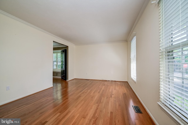 unfurnished room featuring crown molding, light wood-style flooring, and baseboards