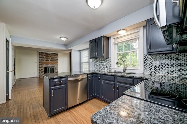 kitchen featuring dishwasher, a sink, a peninsula, and light wood-type flooring