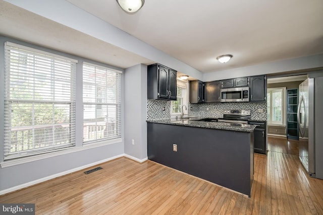 kitchen with stainless steel appliances, tasteful backsplash, wood-type flooring, and baseboards
