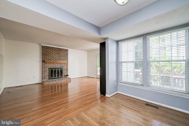 unfurnished living room featuring wood finished floors, baseboards, and a fireplace