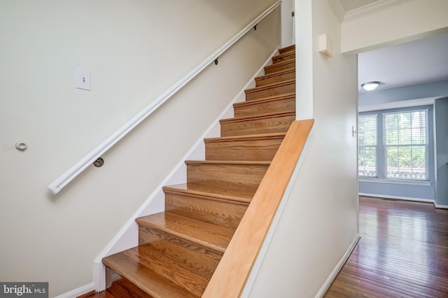 staircase with baseboards, wood finished floors, and crown molding