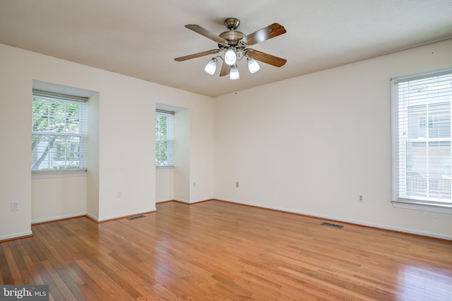 empty room featuring light wood finished floors, baseboards, and a ceiling fan