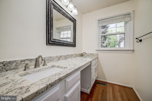 bathroom featuring wood finished floors, double vanity, and baseboards