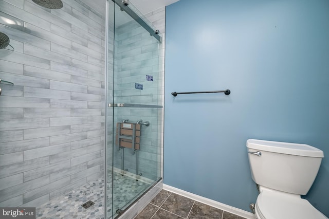 bathroom featuring a shower stall, baseboards, toilet, and tile patterned floors