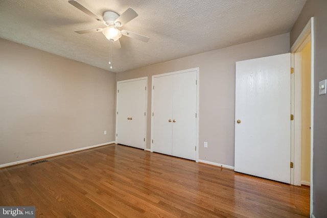 unfurnished bedroom with wood finished floors, baseboards, a textured ceiling, and ceiling fan