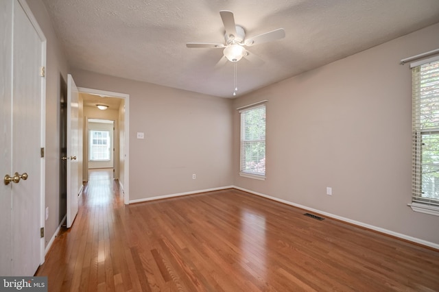 spare room with wood finished floors, ceiling fan, baseboards, and a textured ceiling