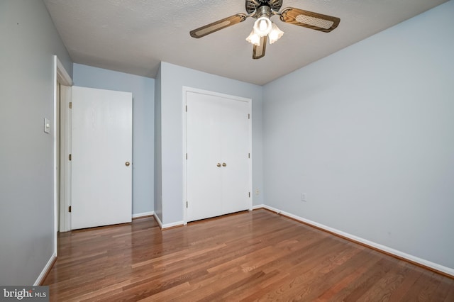 unfurnished bedroom featuring wood finished floors, baseboards, and a closet