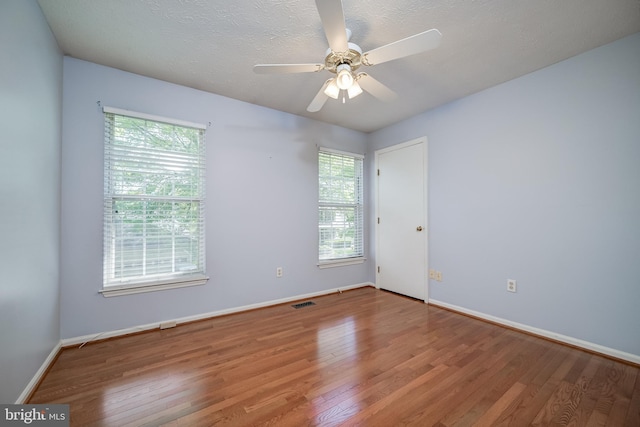 spare room with healthy amount of natural light, wood finished floors, and baseboards