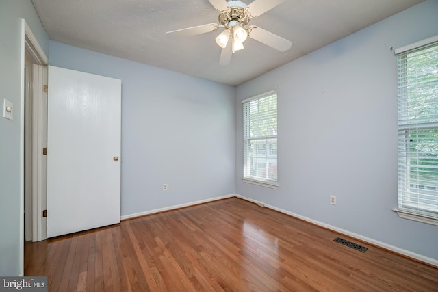 unfurnished room featuring wood finished floors, plenty of natural light, baseboards, and a ceiling fan