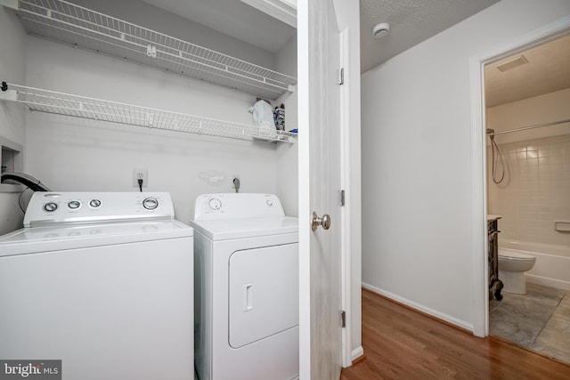 laundry room with independent washer and dryer, wood finished floors, and baseboards