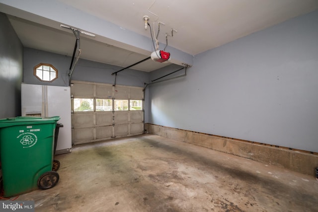 garage featuring freestanding refrigerator and a garage door opener