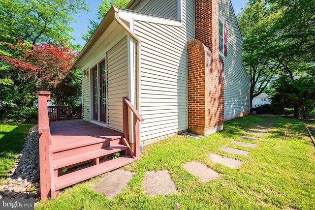 view of side of property with a deck, a yard, and a chimney