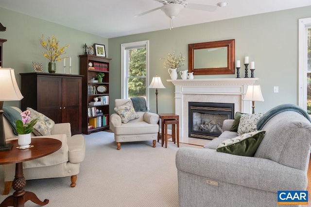 carpeted living area with a glass covered fireplace and a ceiling fan