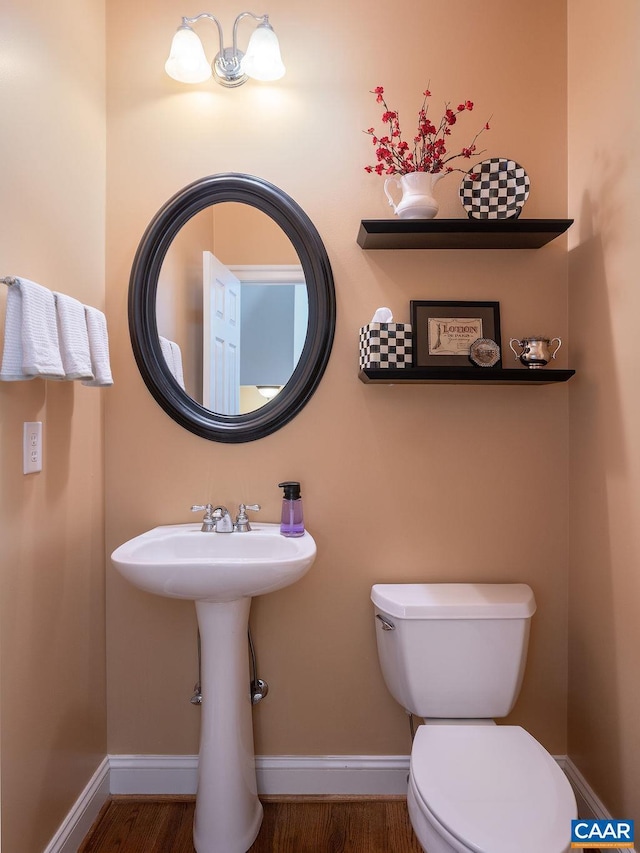 bathroom with baseboards, wood finished floors, and toilet