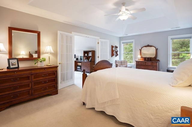 bedroom with a tray ceiling, light colored carpet, multiple windows, and french doors
