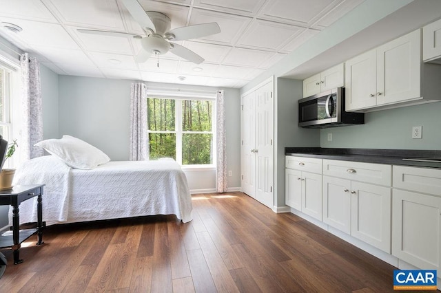 bedroom featuring dark wood-style flooring, baseboards, an ornate ceiling, and a ceiling fan