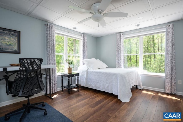 bedroom with dark wood-type flooring, baseboards, an office area, and a ceiling fan