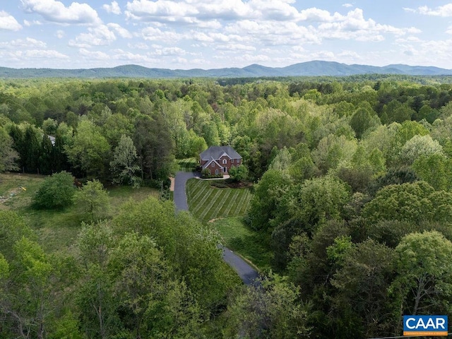 view of subject property featuring a heavily wooded area and a mountain backdrop