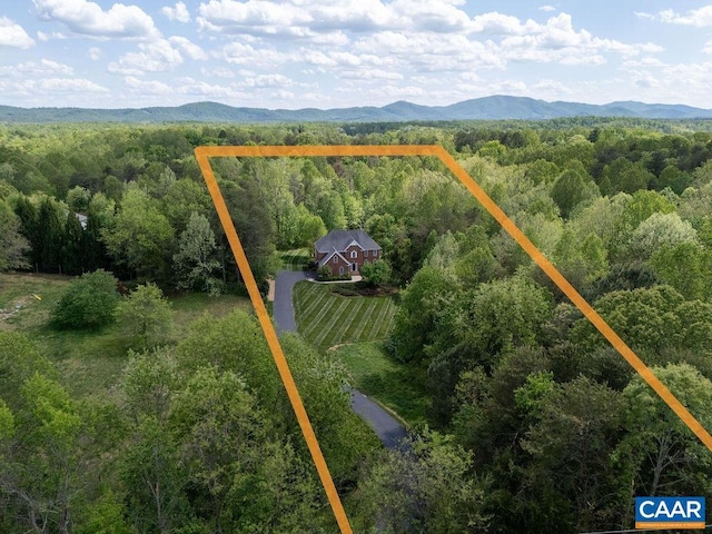 view from above of property featuring a forest, property boundaries highlighted, and mountains