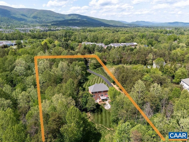 view of property location with a heavily wooded area, property parcel outlined, and a mountain backdrop