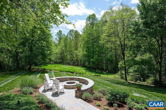 surrounding community featuring an outdoor fire pit, a lawn, and a view of trees