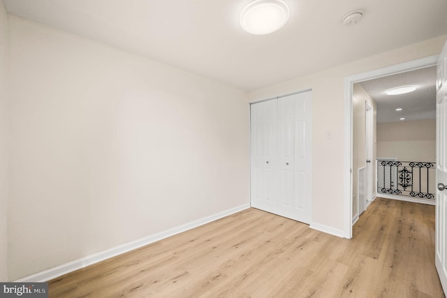 unfurnished bedroom with light wood finished floors, a closet, and baseboards