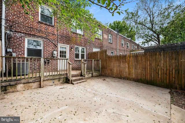 rear view of property with a patio area, brick siding, and fence
