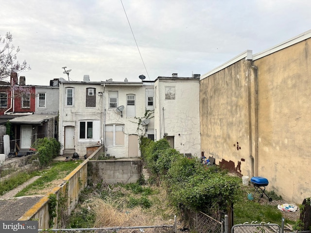 rear view of property with stucco siding and fence