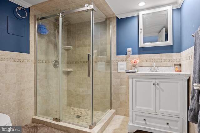 full bathroom with tile walls, a shower stall, vanity, wainscoting, and toilet
