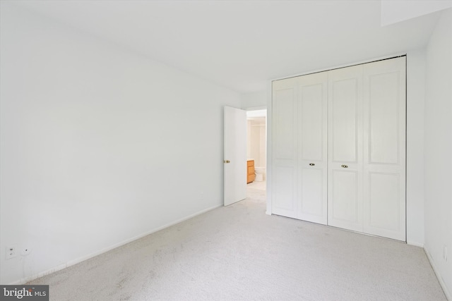 unfurnished bedroom with a closet and light carpet