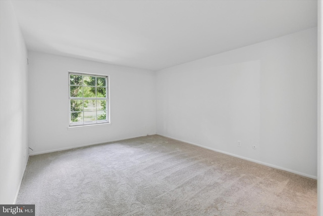 carpeted spare room featuring baseboards